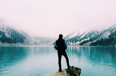 Man Standing Near a Mountain Lake