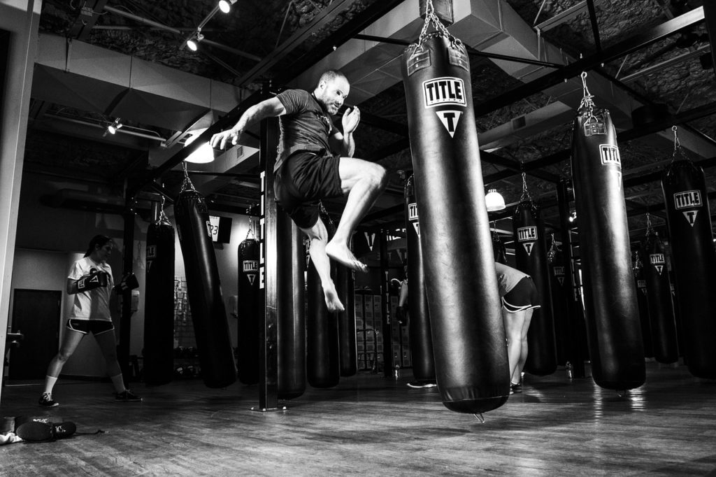 Self-defense - man kicking heavy bag in a gym