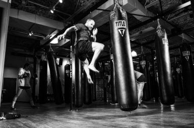 Self-defense - man kicking heavy bag in a gym